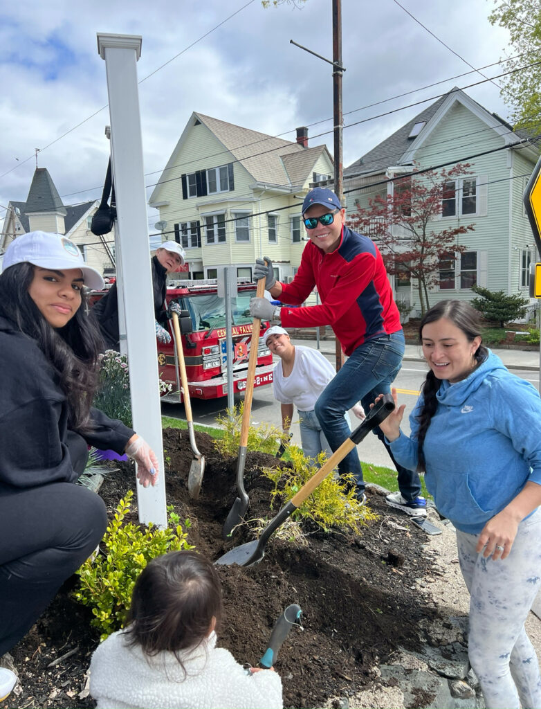 cepeda2 | The Diamant Foundation Group of volunteers planting a shrub in a curbside garden with a red fire truck and houses in the background.”,